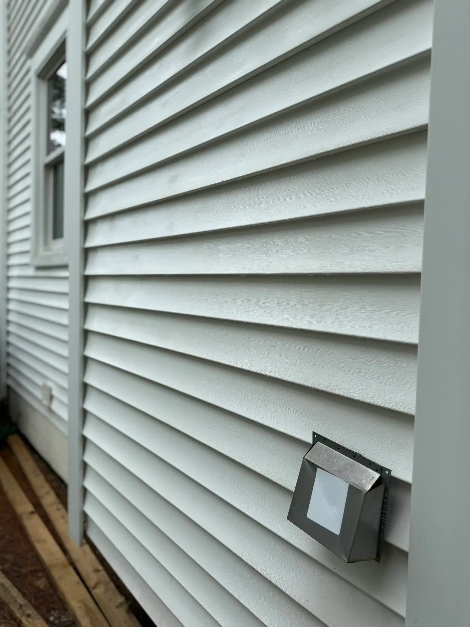 The same white vinyl wall rinsed clean and algae-free after a soft wash